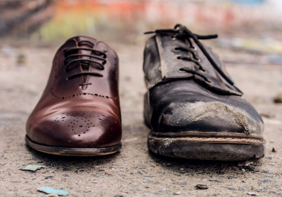 Conceptual shooting of shoes. Old shabby shoes in comparison with new and expensive ones.