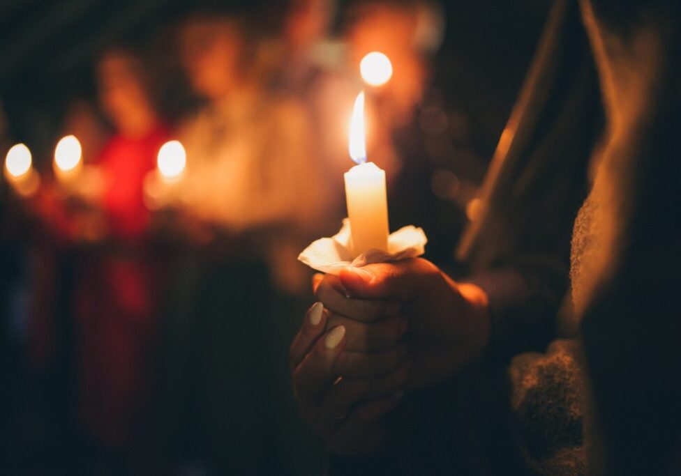 a girl holds a lighted candle in her hands, a religious traditio